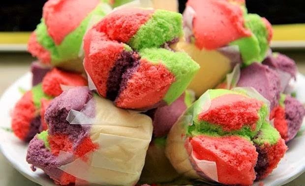 Colorful steamed buns in pink, green, and purple hues piled on a plate, vibrant festive mood, warm tones.